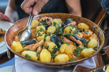 Bowl of traditional stew with potatoes and seafood in Portugal