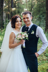 Beautiful portrait of happy bride and groom on green forest background