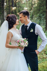 Beautiful portrait of happy bride and groom on green forest background