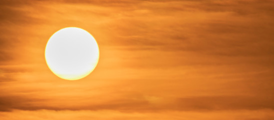 Extreme close up of the sun setting with dramatic red clouds at sunset. Squared image. High...