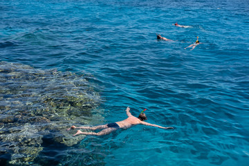 tourists snorkel in crystal turquoise water