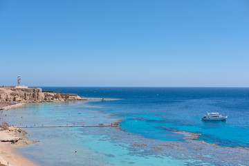 group of people, adults and children, with diving masks and snorkels swimming underwater in sea. White ship and boat on clear sky. Idyllic summer vacation activity