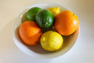 Citrus fruit in a white bowl. Lemons limes and oranges