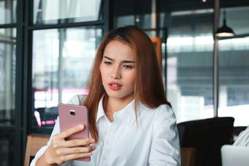 Fototapeta premium Shocked young Asian business woman with mobile smart phone in office. Internet of things concept.