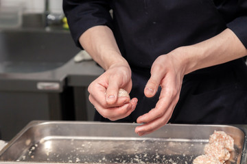 Chef hands creating, forming, breading chicken cutlet with knife on professional restaurant kitchen. Concept fast food business, preparation for cooking, menu, gastronomy, burgers, patty, meatballs