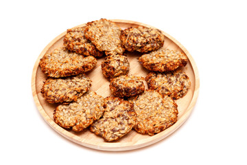 Closeup homemade natural oatmeal dietary lean cookies with seeds on a round wooden plate isolated on a white background. The concept o healthy low-calorie diet, weight loss, sugar dependence