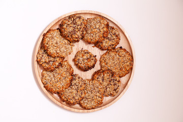 Closeup homemade natural oatmeal dietary lean cookies with seeds on a round wooden plate isolated on a white background. The concept o healthy low-calorie diet, weight loss, sugar dependence