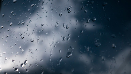 Raindrops on glass and blurred blue sky and clouds