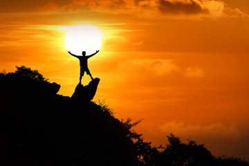 Man standing on the top of the mountain looking at red sky sunset