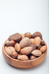 Different kinds of nuts in shell. Hazelnut, walnut, almond and brazil nuts in wooden bowl, vertical, copy space