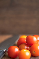 Fresh tomatoes on wooden table over bokeh background white knife beside