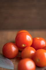 Fresh tomatoes on wooden table over bokeh background white knife beside