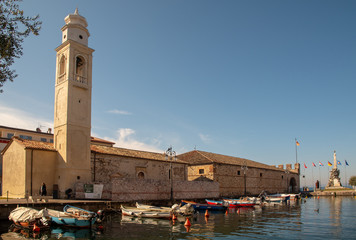 Fototapeta na wymiar Scenic view of the Old Port of Lazise with the back of the Church of St Nicolò and docked boats, Veneto, Italy