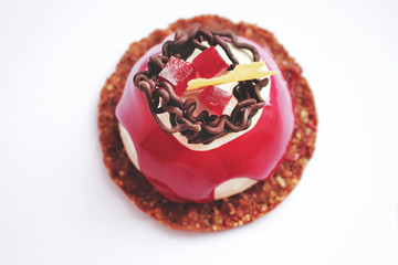 Red and white dessert with chocolate decoration, red jelly and cookie base