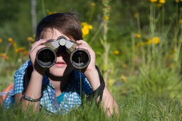 Boy young researcher exploring with binoculars environment in summer garden