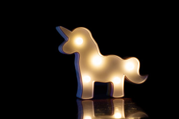 figure of a white glowing horse on a black background with a beautiful reflection