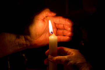 two hands hold a burning candle