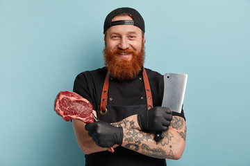 Headshot of cheerful friendly lookig butcher cuts meats in variety of piece, prepares for sale in...