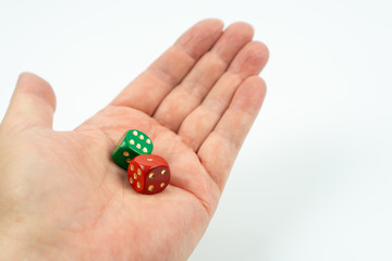 A hand holding a green dice and a red dice, white background