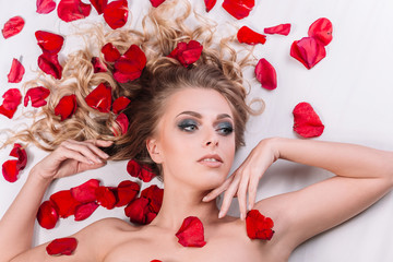Obraz na płótnie Canvas beautiful female model relaxing in the Wellness center, lying among the rose petals.