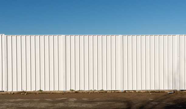 Three panels of a white security fence