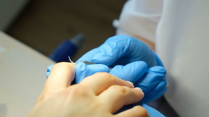 Beautician trimming cuticles of female client. Manicure and skincare. Woman in spa beauty salon. Close up of hands.