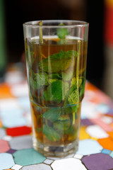 Typical Moroccan fresh mint tea in a glass on a picturesque mosaic table (Morocco, Africa)