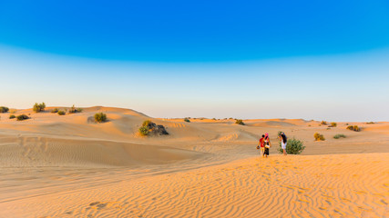 Fototapeta na wymiar Couple over sand dunes during a jeep safari in Dubai Desert Conservation Reserve, United Arab Emirates. Copy space for text.