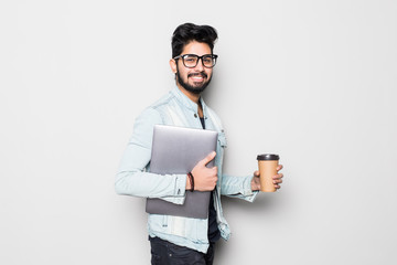Young indian man holding laptop and take away coffee white standing on white background