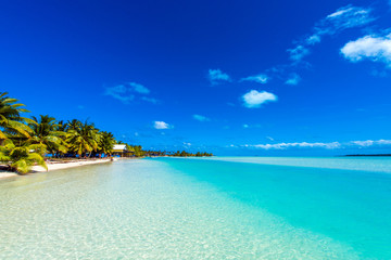 Stunning tropical Aitutaki island with palm trees, white sand, turquoise ocean water and blue sky...
