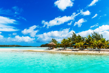 Fototapeta na wymiar Stunning tropical Aitutaki island with palm trees, white sand, turquoise ocean water and blue sky at Cook Islands, South Pacific. Copy space for text.