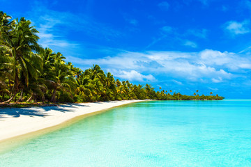 Stunning tropical Aitutaki island with palm trees, white sand, turquoise ocean water and blue sky at Cook Islands, South Pacific. Copy space for text.