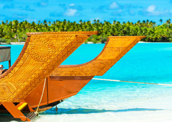 Wooden carved boat on a sandy beach in Aitutaki island, Cook Islands, South Pacific. With selective focus.