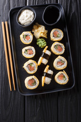 Tamagoyaki sushi roll with rice, cheese, salmon and avocado closeup on a plate. vertical top view