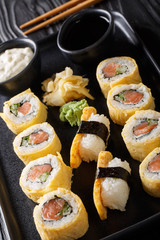 Tamagoyaki sushi roll with rice, cheese, salmon and avocado closeup on a plate. vertical