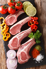 Fresh raw lamb chops on the bone with vegetable ingredients close-up. vertical top view 