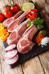 Uncooked lamb chops with fresh vegetable ingredients and spices close-up. vertical