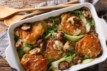 chicken thighs with baby bok choy, shiitake mushrooms and cheese sauce in a rustic style close-up. horizontal top view from above - obrazy, fototapety, plakaty