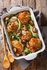 Baked chicken thighs with baby bok choy, cheese and mushrooms close-up. vertical top view