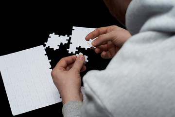 a man assembles puzzle piece on black background