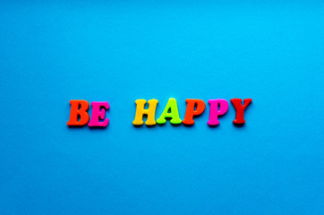 text be happy from plastic magnetic letters on blue background