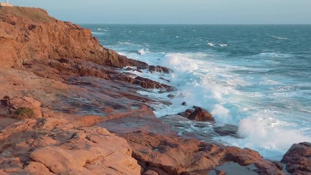 Onde del mare che si infrangono sulla scogliera rocciosa al rallentatore.