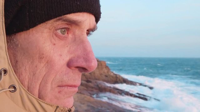 Vecchio pescatore sta osservando il mare tempestoso in cima a una scogliera la mattina all'alba.