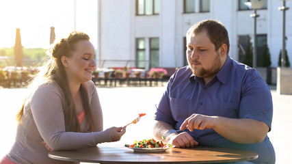 Fat couple eating fresh vegetable salad at outdoor date, health care, calories