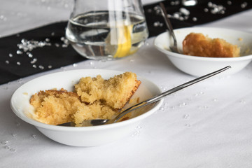 Sponge dessert in white bowl with spoon on a table laid out for a party