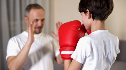 Little boy boxing with his step-father, learning attacking, family togetherness