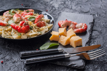 Pasta with shrimp and stylish Cutlery on a black background. Italian cuisine. The concept of healthy eating.