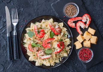Macaroni with shrimp and cheese slices with stylish Cutlery on black background. Italian cuisine. The concept of healthy eating. The view from the top.