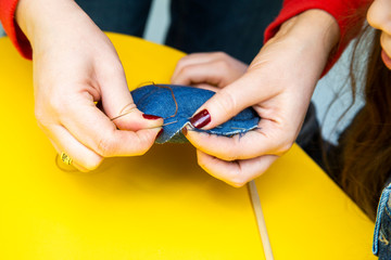 female hands with manicure sew a toy from a dark blue fabric, show how to sew