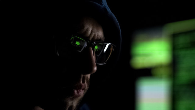Man in hoodie wearing glasses with app synchronized with computer, digital eye